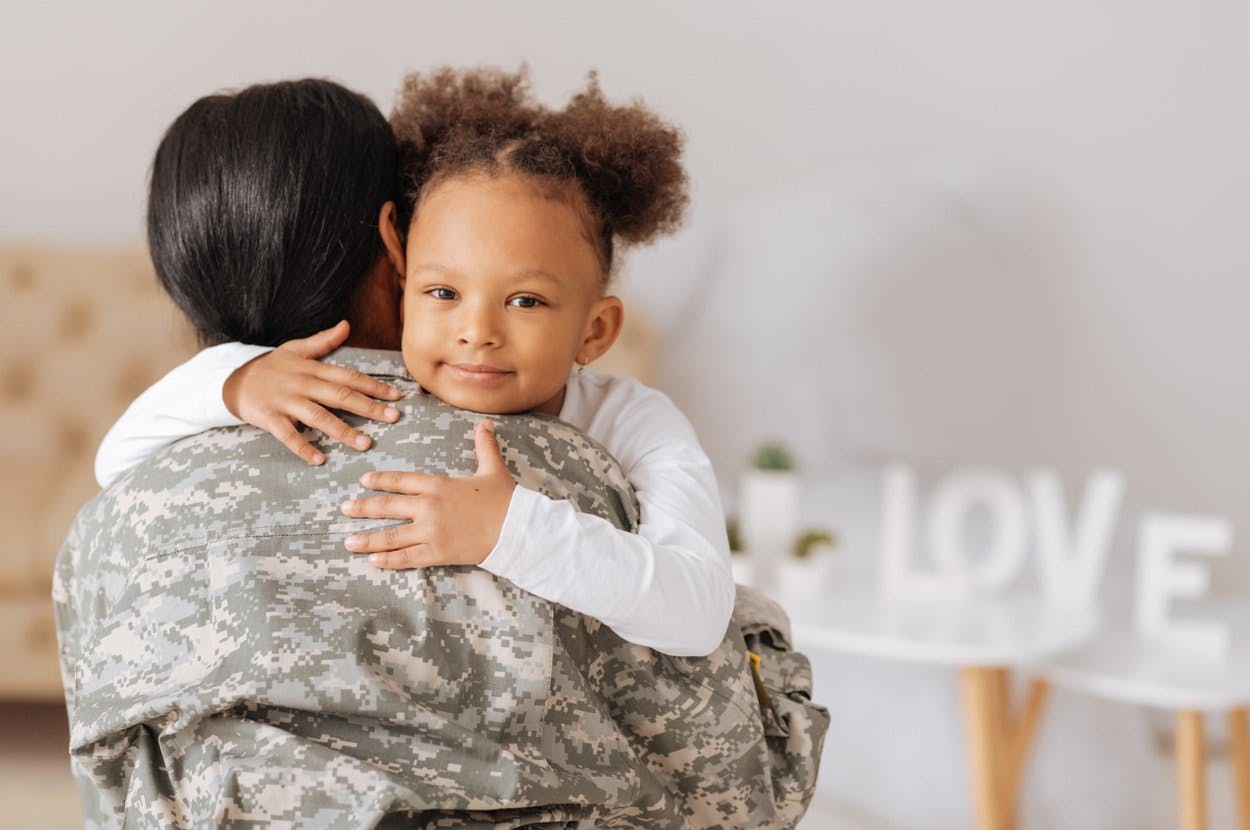 little girl hugs soldier mom
